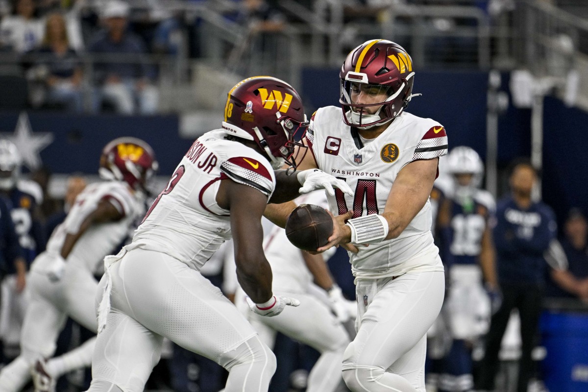 Washington Commanders running back Brian Robinson Jr. takes the handoff from quarterback Sam Howell.